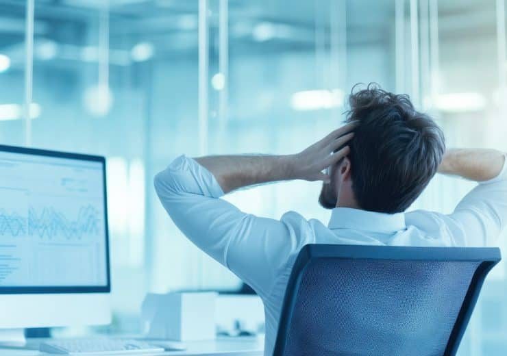 Taking a Moment to Breathe: A businessman leans back in his chair, hands behind his head, with a contented sigh, suggesting a moment of relaxation and accomplishment in the midst of a busy workday.